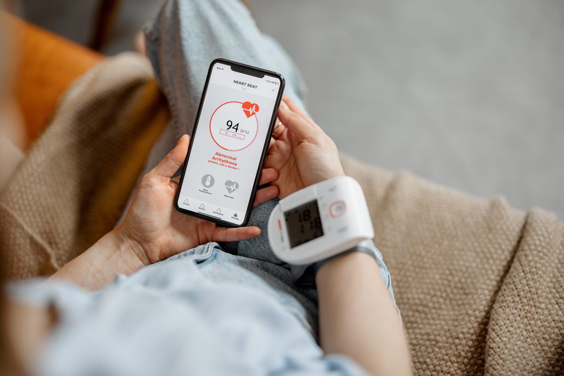 Woman measure heart rate and pressure with smart technology in phone while sitting on sofa at home. Health and wellness concept.